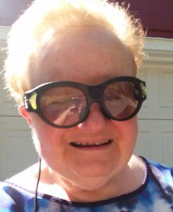 Betsey is wearing her Aira glasses with a big smile